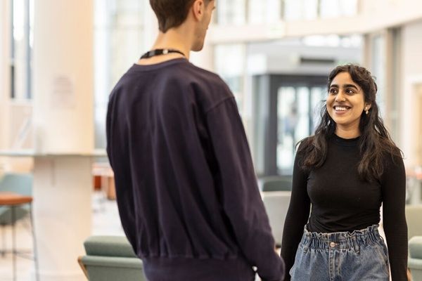 Two students chatting in a light modern space on campus