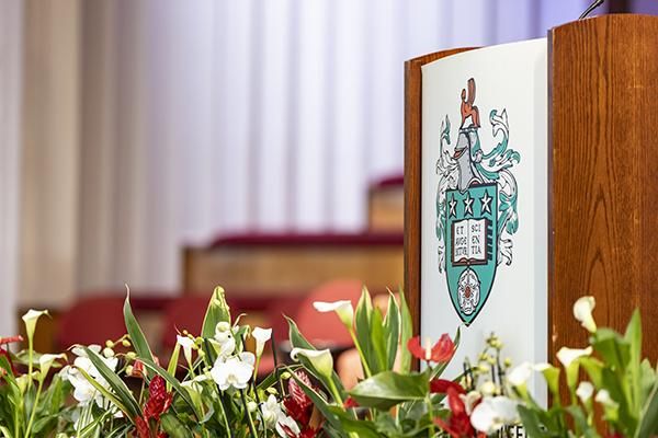 University of Leeds crest on a podium surrounded by flowers on graduation day