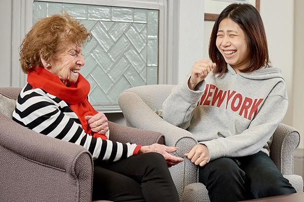 MA student volunteer sitting and laughing with their penpal from the Writing Back programme