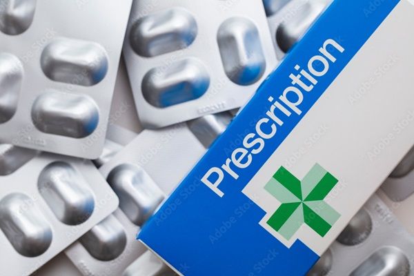 Blister packs of medicine pills nest to a box that says 'prescription' on it.