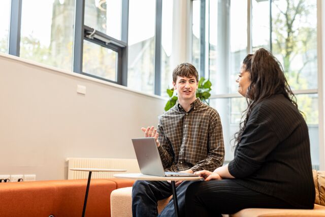 Two people sit and discuss work inside Student Support Services in the Marjorie and Arnold Ziff building.
