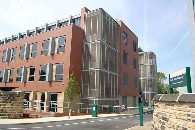 An exterior shot of the Charles Thackrah Building. On the right hand side is a sign with the building name on next to a gate