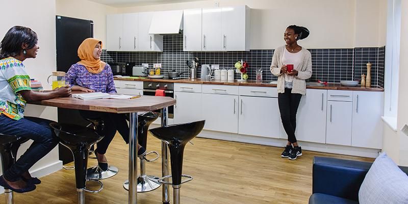 Three students chatting in a kitchen in student accommodation