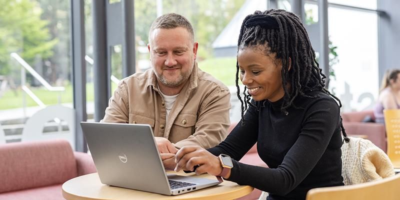 Two people sitting working together on a laptop