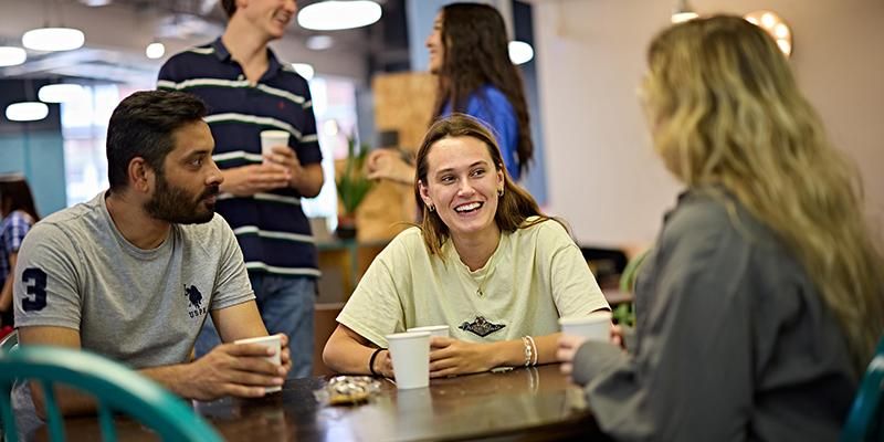 Three students sitting around a table chatting at Global Café.