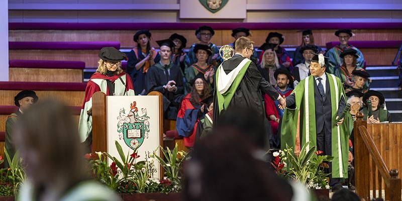 Graduate shaking hands with presiding officer Hai-Sui Yu at a graduation ceremony