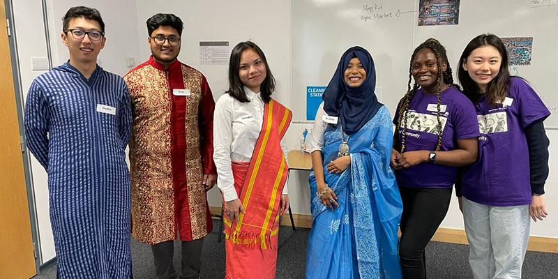 Six intercultural ambassadors standing in a line, some wearing traditional dress from their cultures