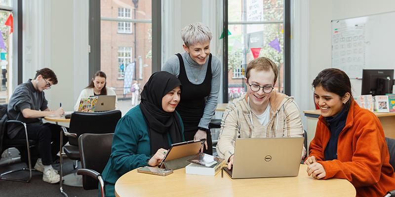 A Lifelong Learning Centre staff member working with three foundation year students sitting around a laptop