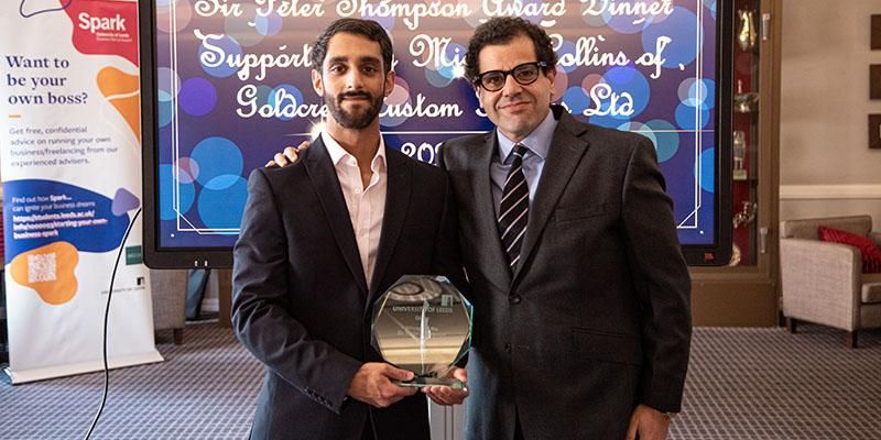 Two people including student founder of Gilly, holding their  Sir Peter Thompson award trophy