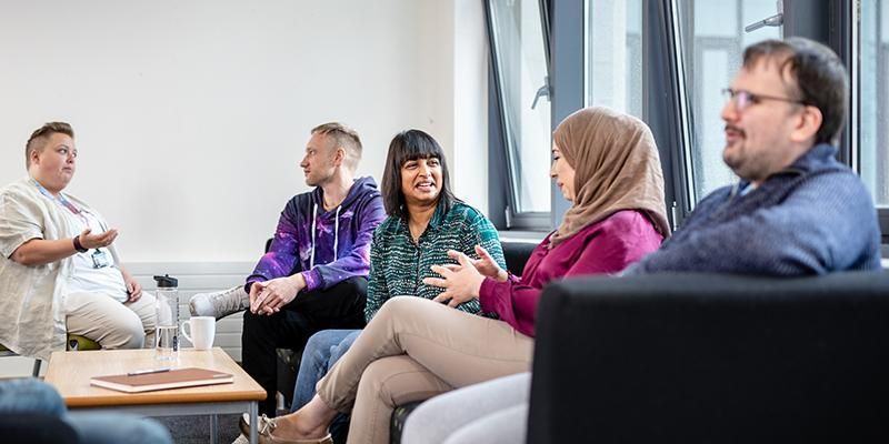 5 students chatting in groups on sofas