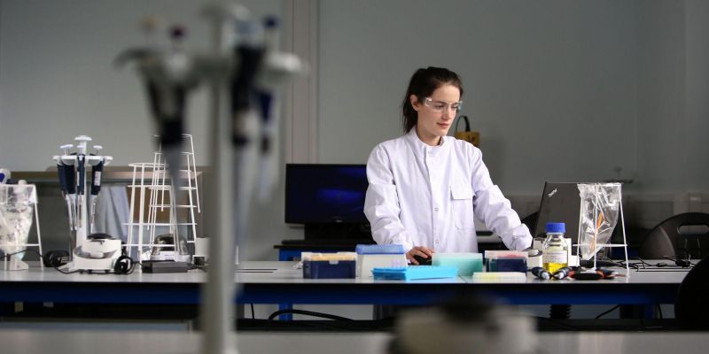 A postgraduate research student works in a laboratory, analysing data on a laptop.