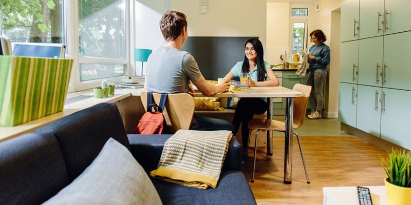 Living space in a flat, in Charles Morris Halls, Dobree and Whetton student residences, with a sofa, dining table and some of the kitchen in view.