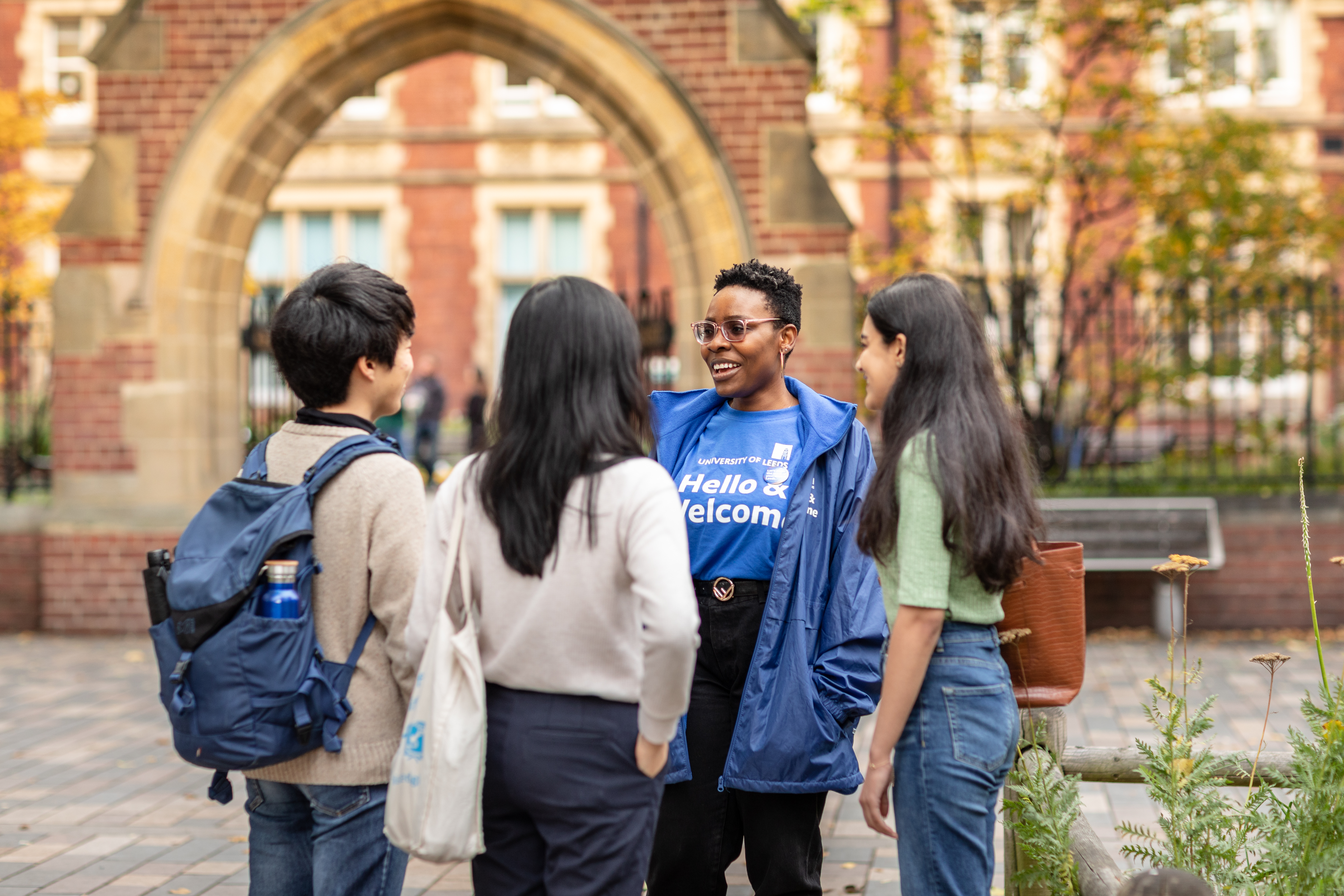 A group of students chatting and an International Welcome Student Assistant answering questions.