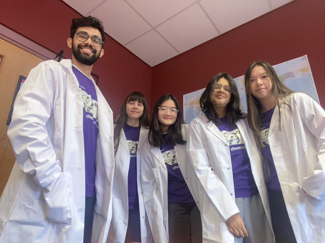 Five female and one male student wearing lab coats and smiling. 