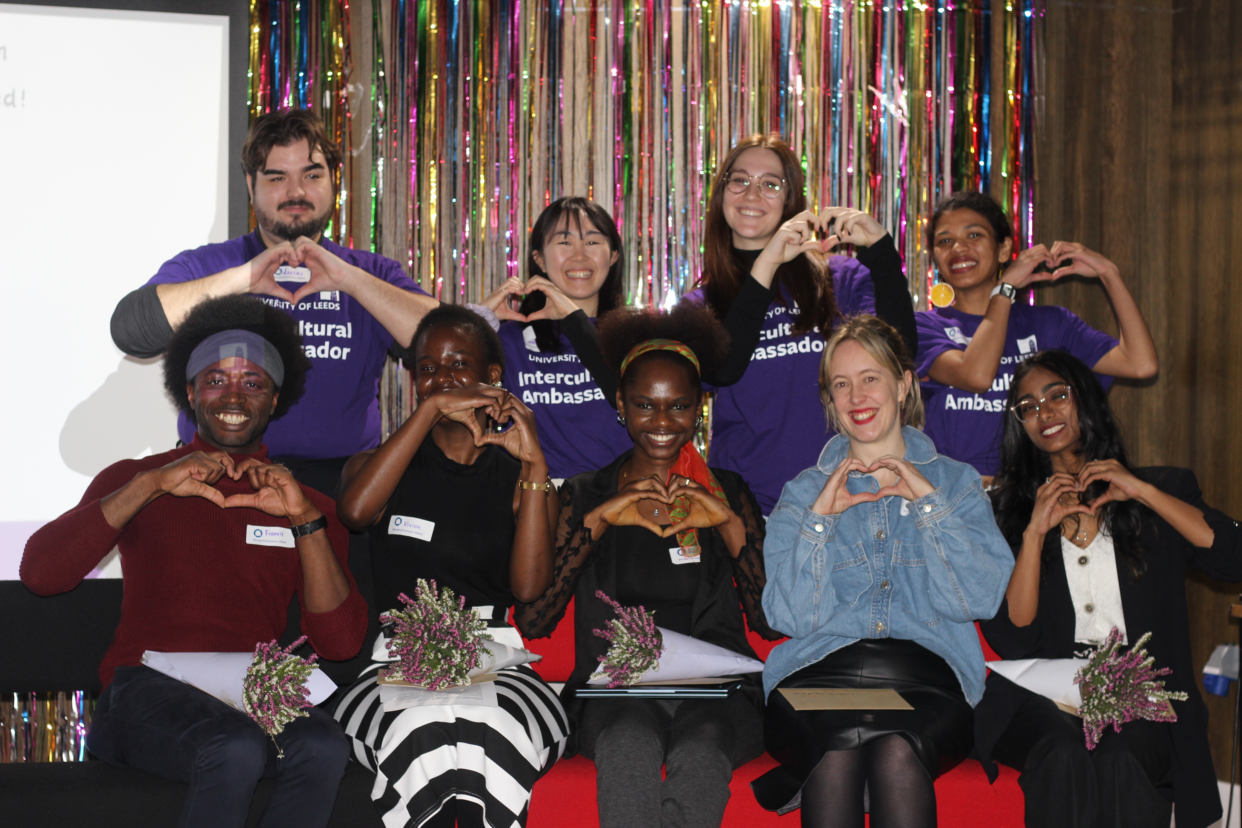 Students and presenters showing a heart shape with their hands.